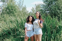 two young women standing in front of tall grass