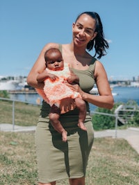 a woman holding a baby in a green dress